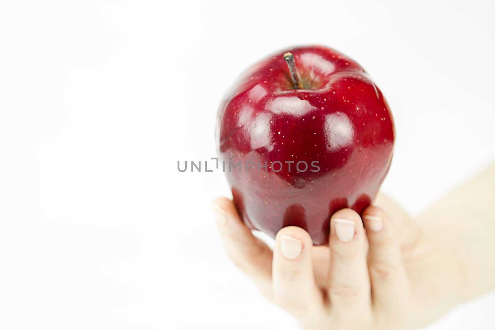 Hand of a young woman holding a red apple like the one offered b by robbyfontanesi