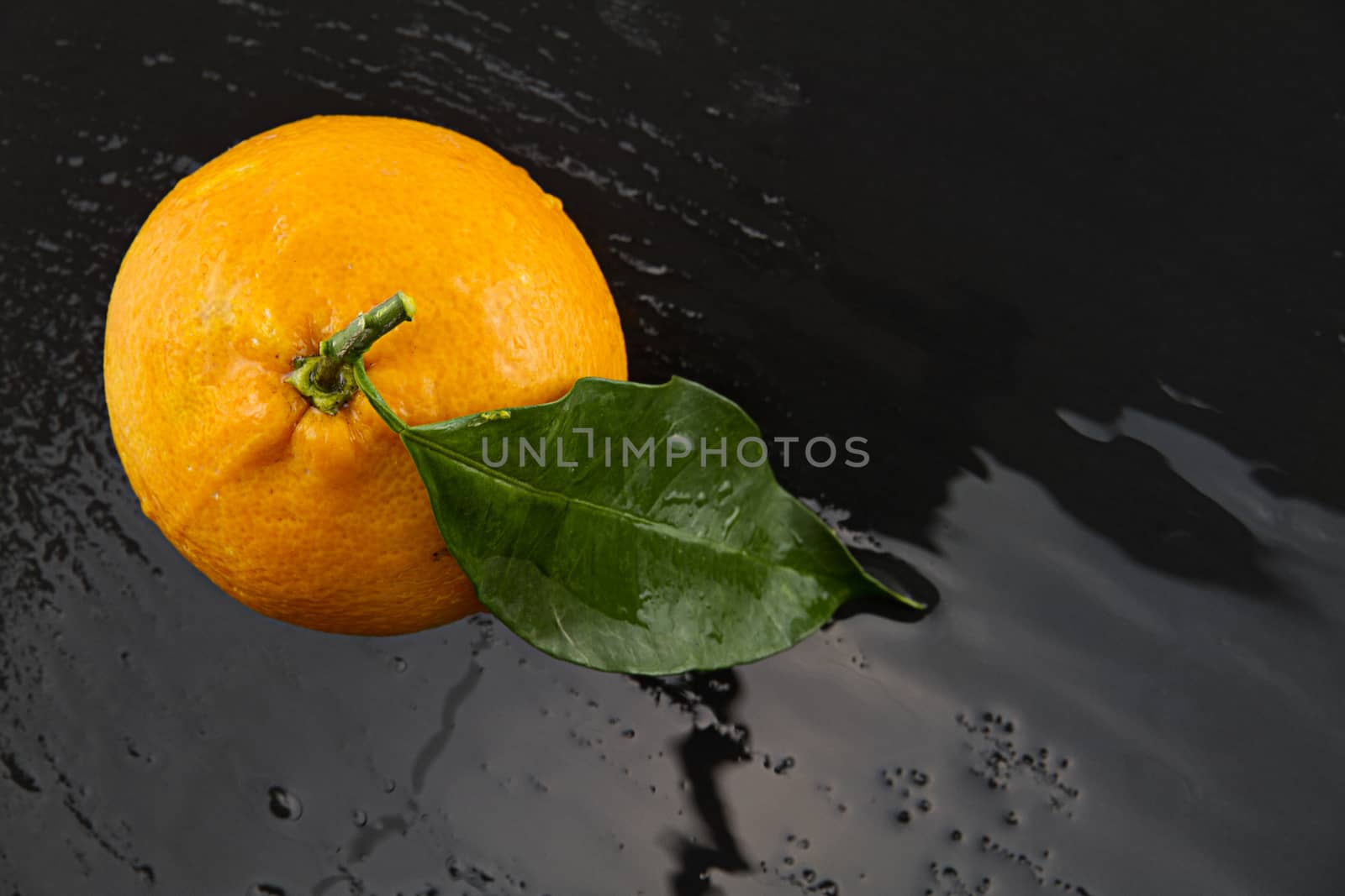 Orange with leaf shot from above on a black  wet slate plate wit by robbyfontanesi