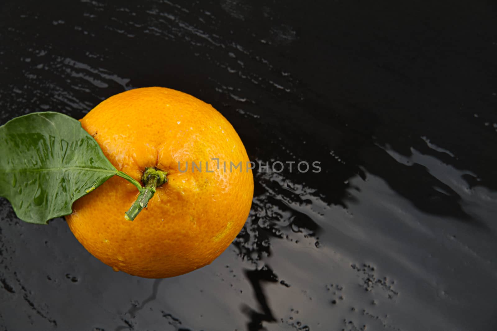 Orange with leaf shot from above on a black  wet slate plate wit by robbyfontanesi