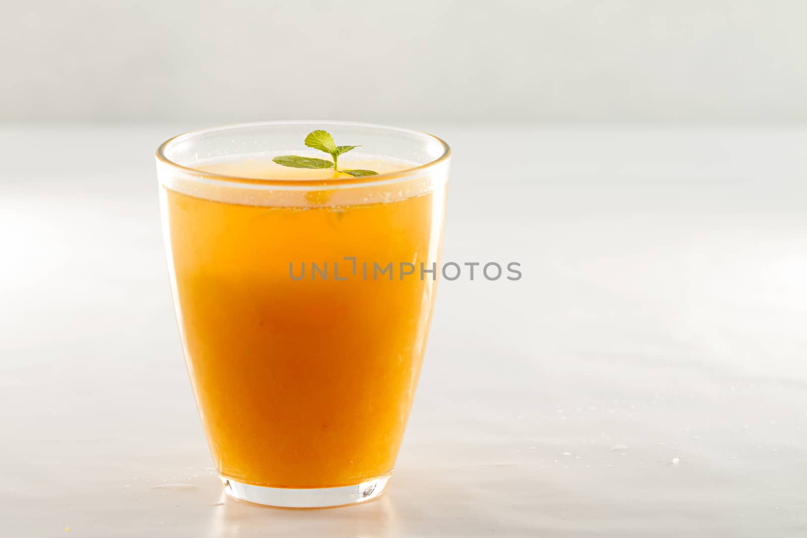 An inviting glass full of orange juice with a fresh mint leaf th by robbyfontanesi