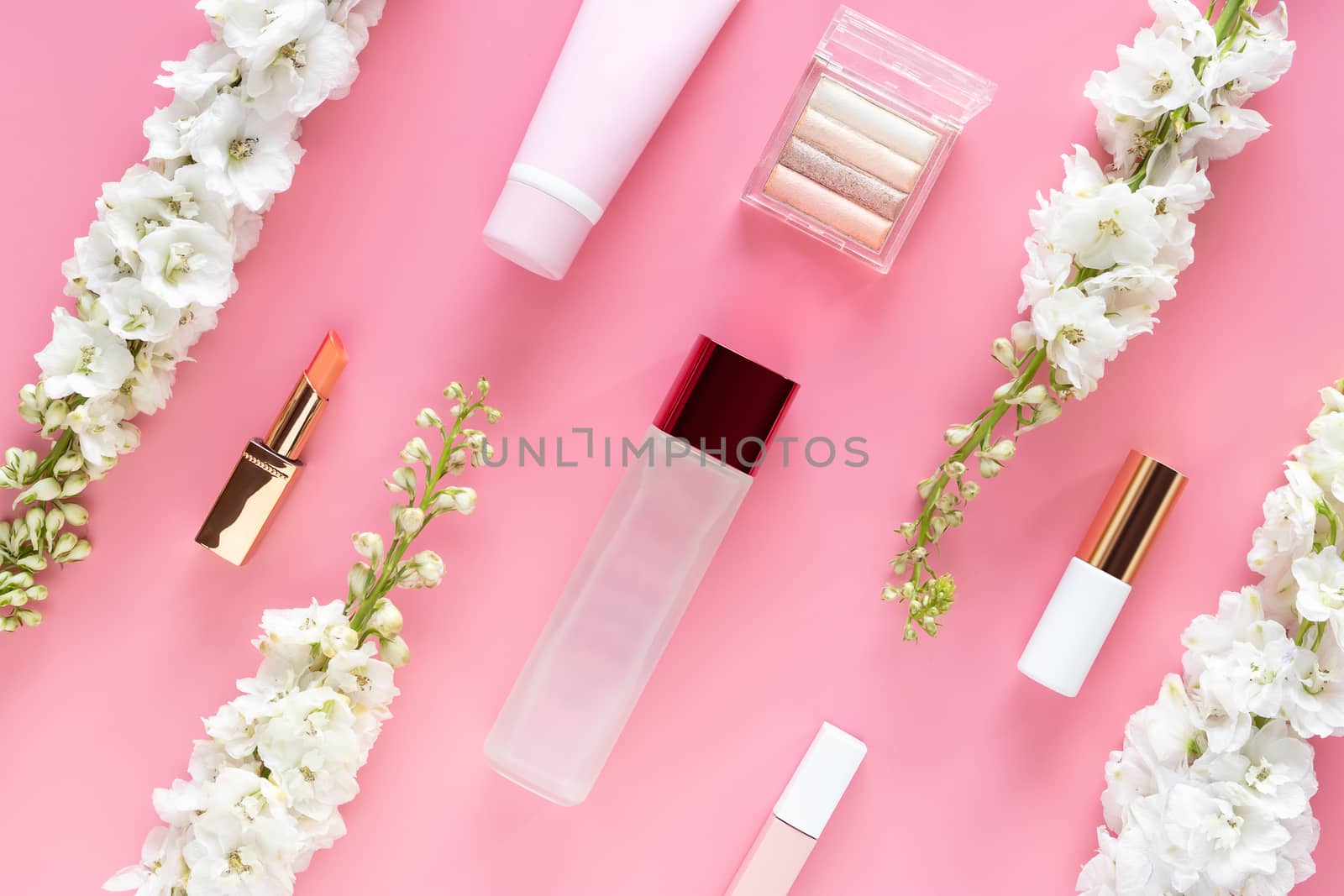 facial cosmetic beauty products with white flower on pastel pink desktop background. natural beauty skin care layout, top view, flat lay.
