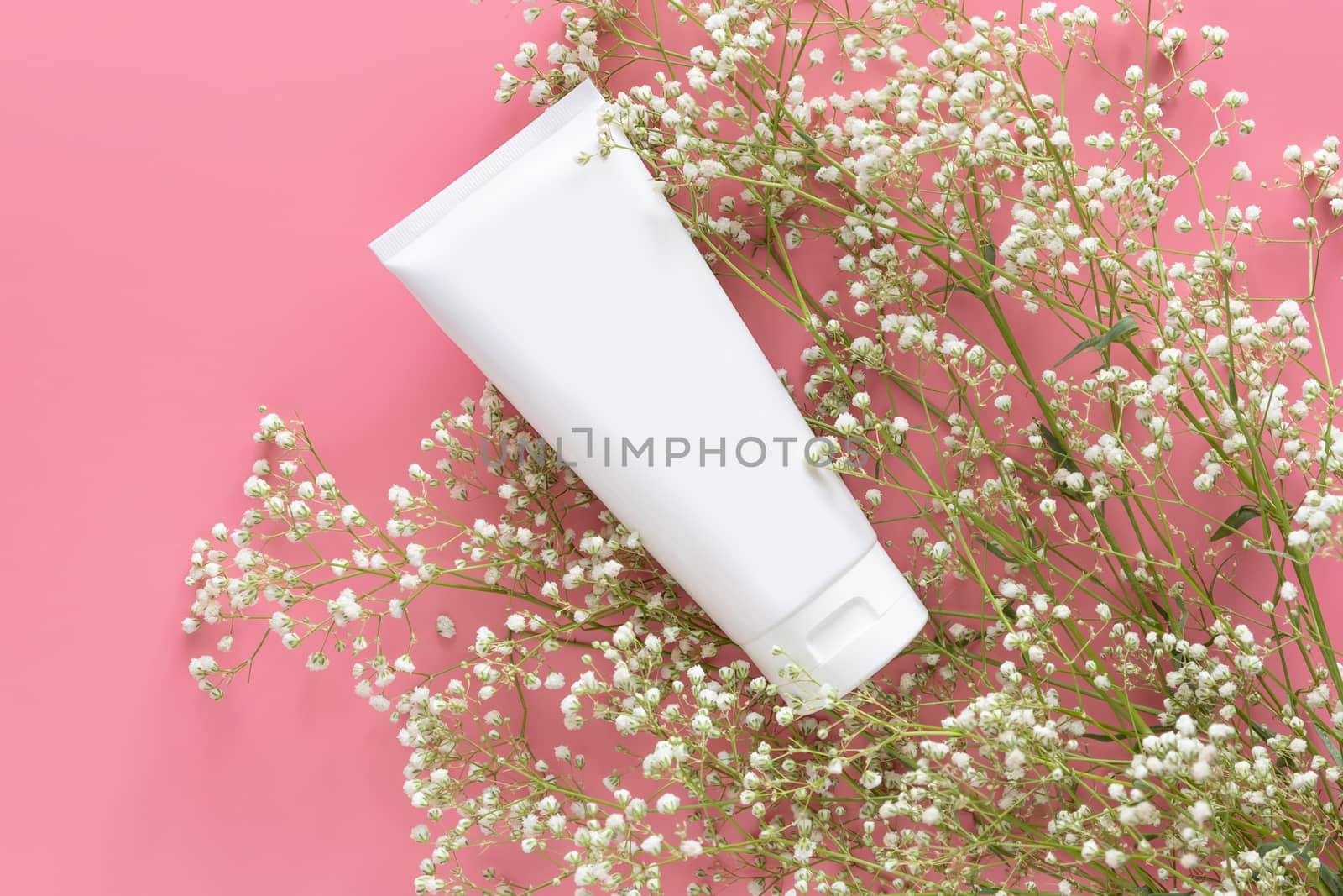 cosmetic nature organic skincare concept. white cosmetic tube container with blank label for branding packaging  mock up, decorate with white flower on pink background with copy space