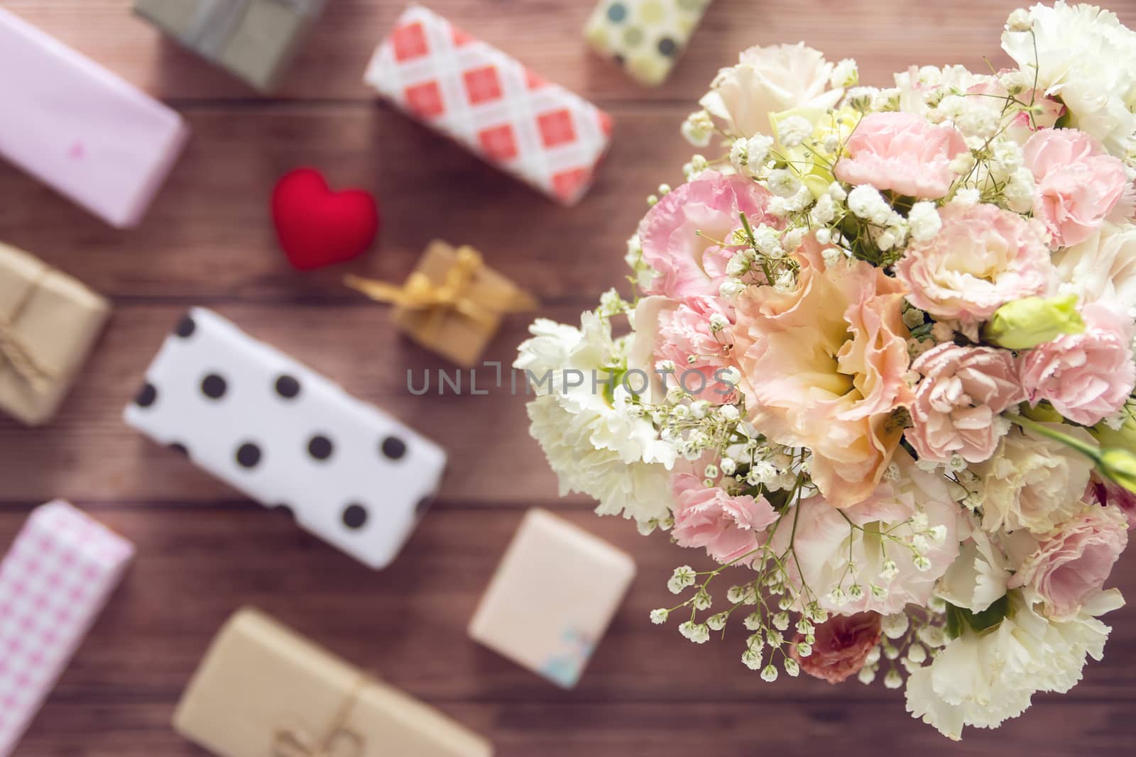 flat Lay of bouquet of beautiful romantic fresh flower with colorful gift box present on wooden background, top view