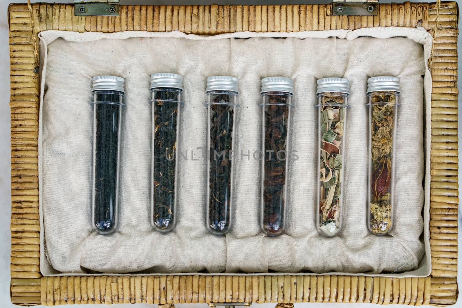 Six tube of different leaf teas collection in wicker basket.