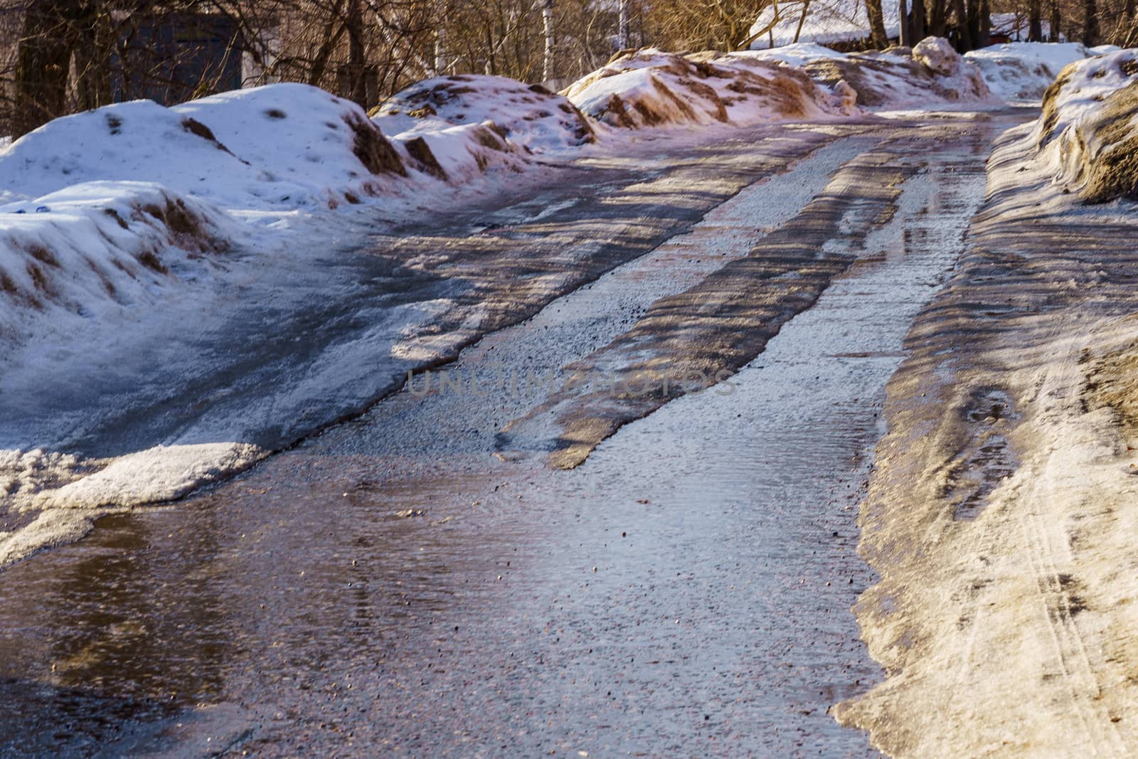 winter road covered with snow and ice with puddles and ruts by VADIM