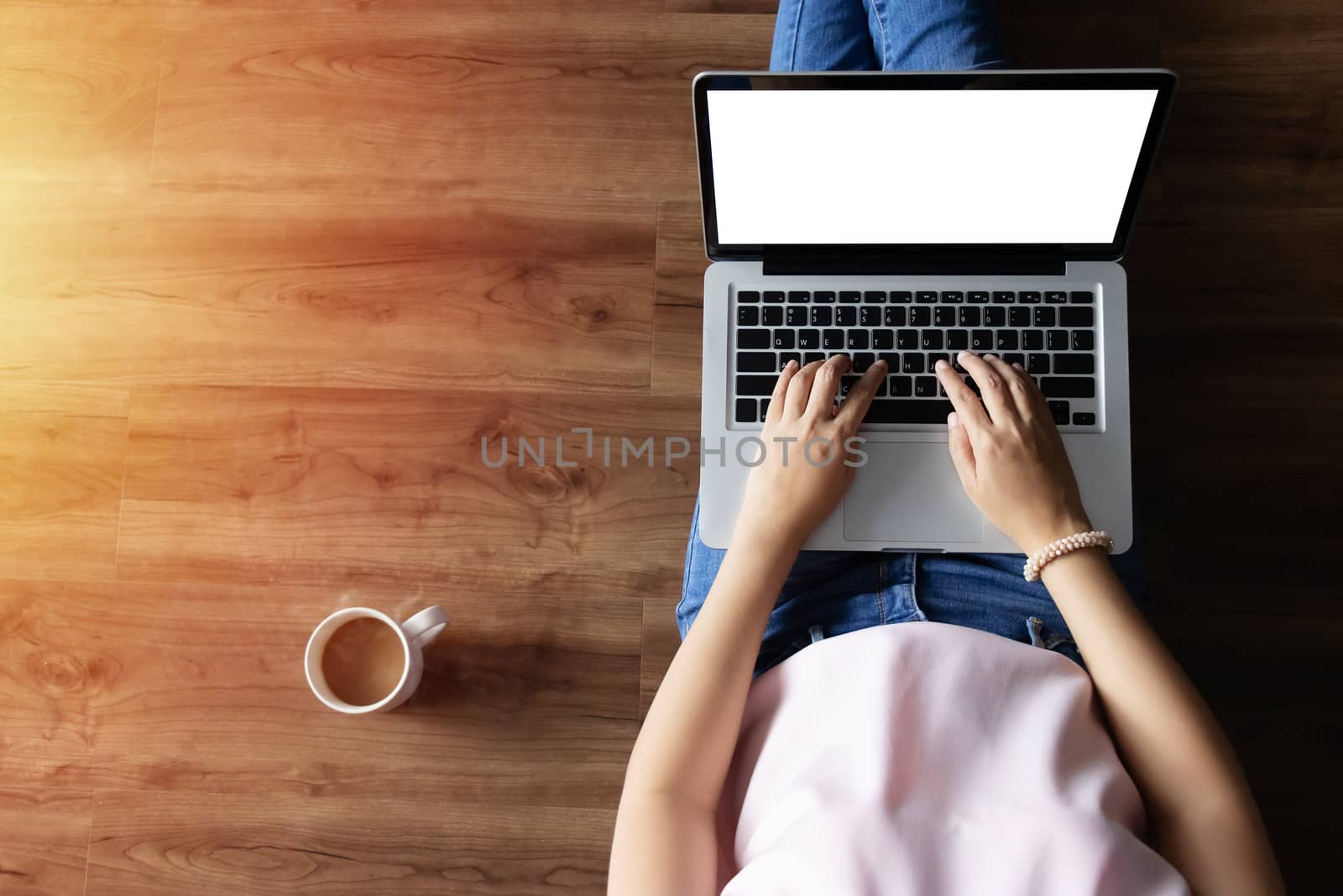 top view of woman typing on laptop computer with blank white screen from home on wooden floor with copy space by asiandelight