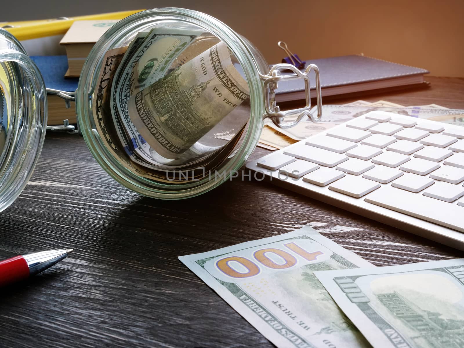 Glass jar with money on the desk. Savings and personal finances concept. by designer491