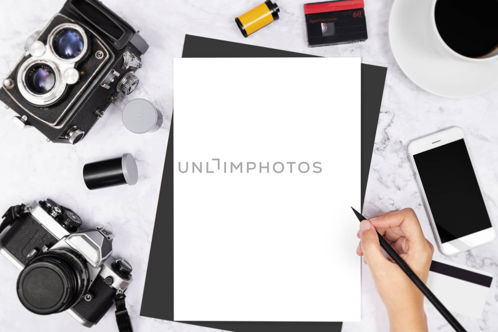 flat lay hand writing in a blank white page notebook decorated with vintage camera and photography tool on white marble background by asiandelight