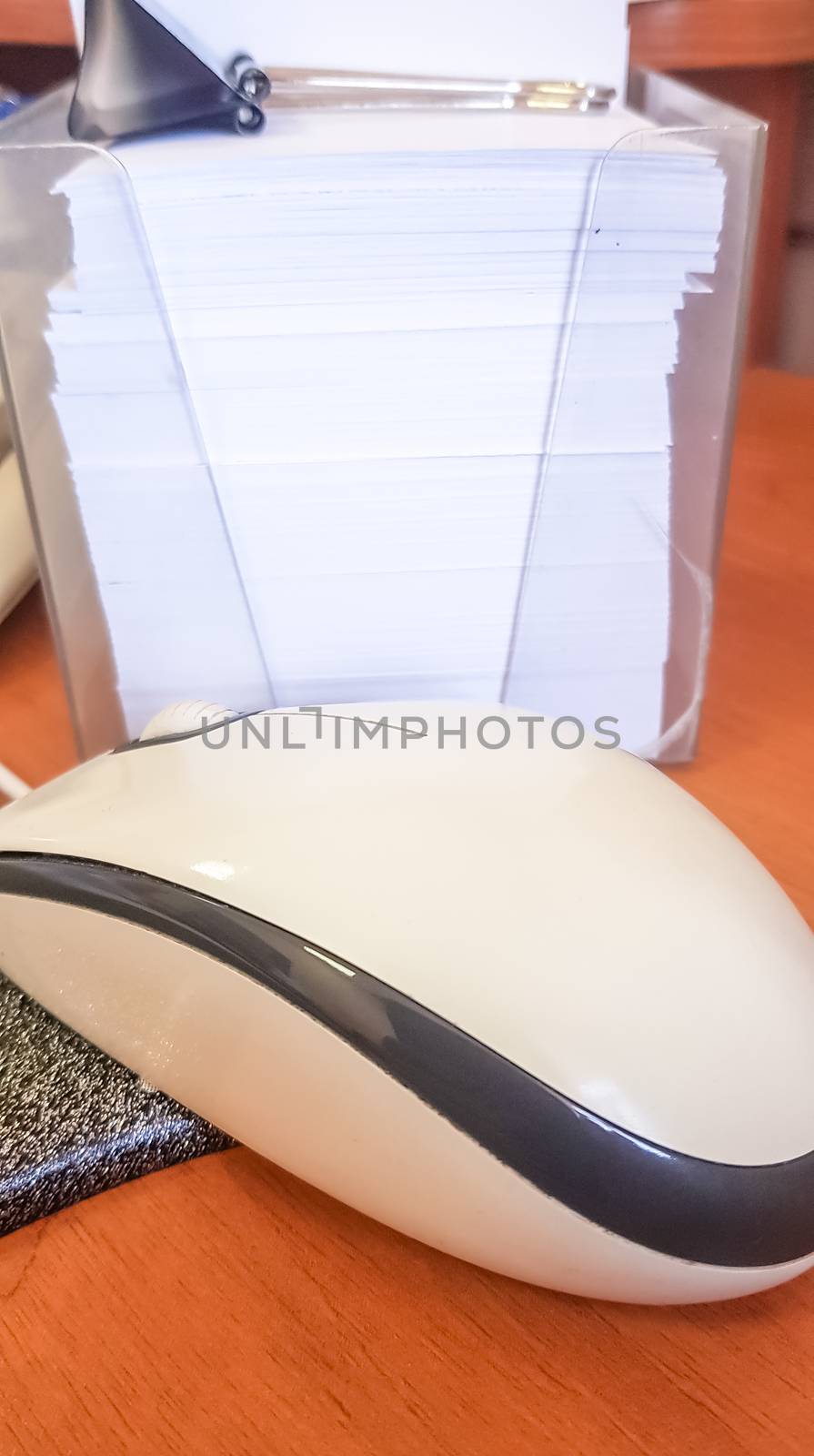 Computer mouse and a stack of notes in a plastic box close-up, vertical photo.