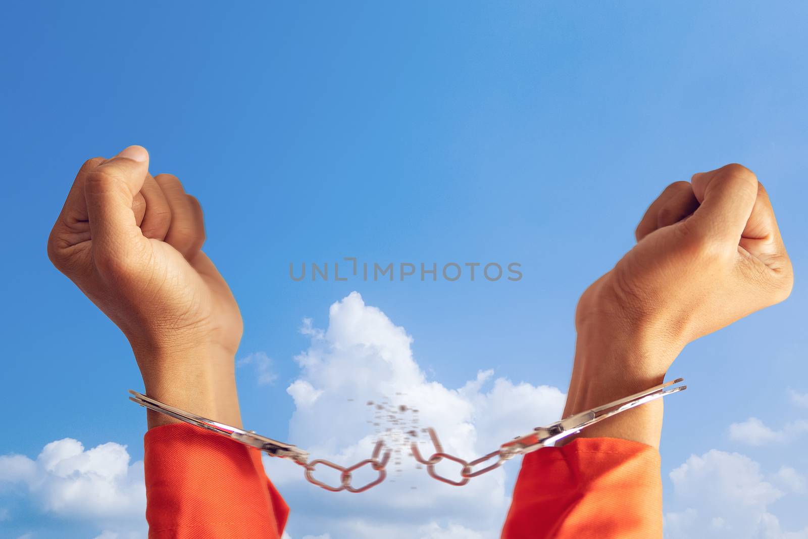 freedom concept. two hands of prisoner with broken handcuff for freedom meaning with blue sky at background by asiandelight