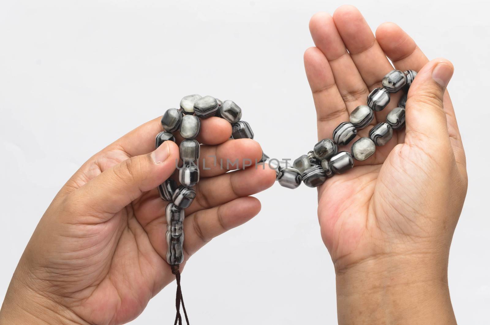 Hand holding muslim beads rosary or tasbih isolated on white background. Selective focus.