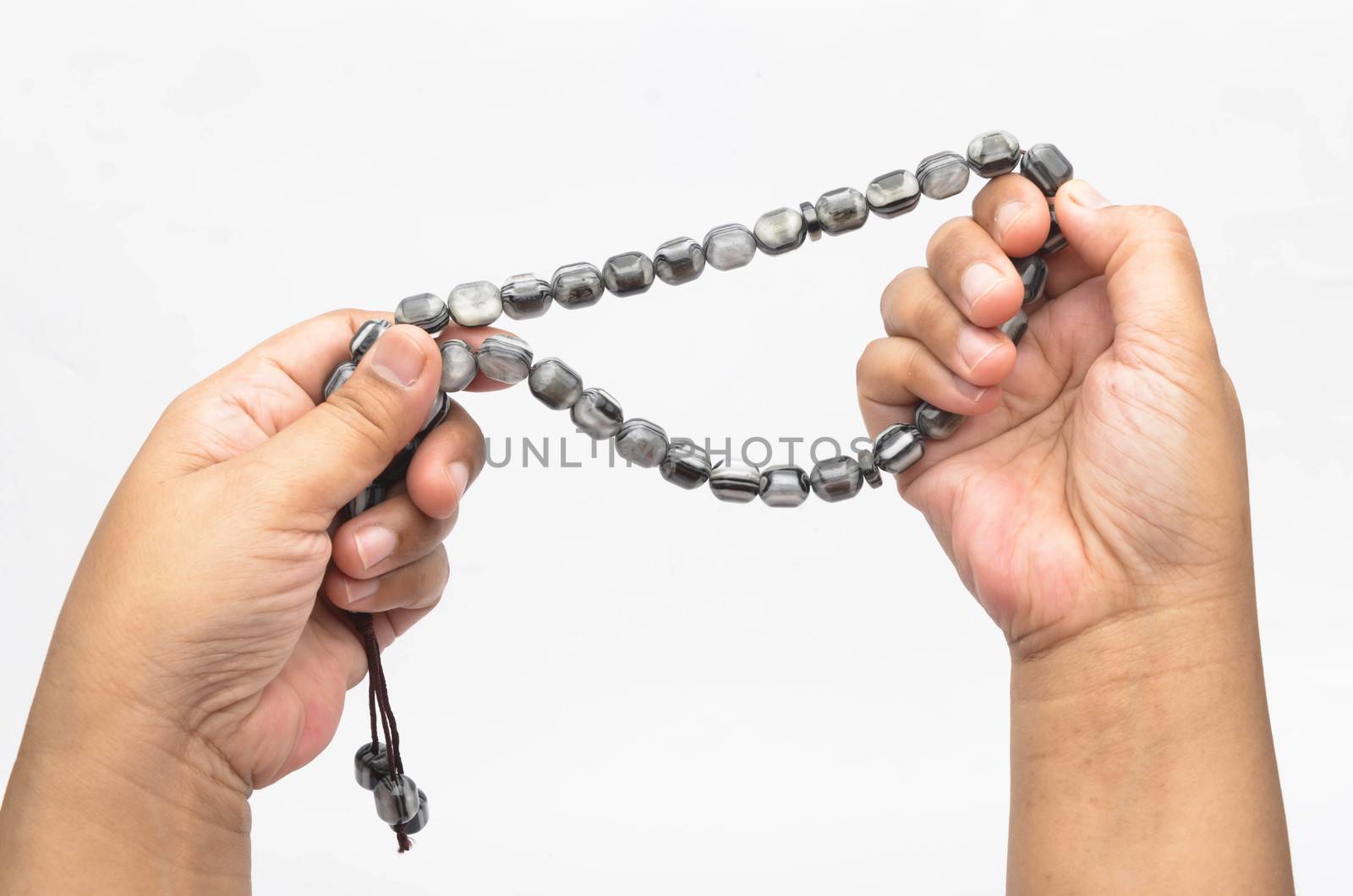 Hand holding muslim beads rosary or tasbih isolated on white background. Selective focus.