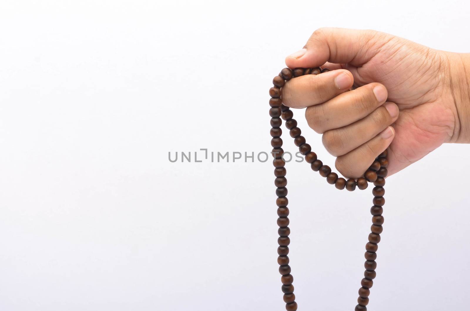 Hand holding muslim beads rosary or tasbih isolated on white background. Selective focus.