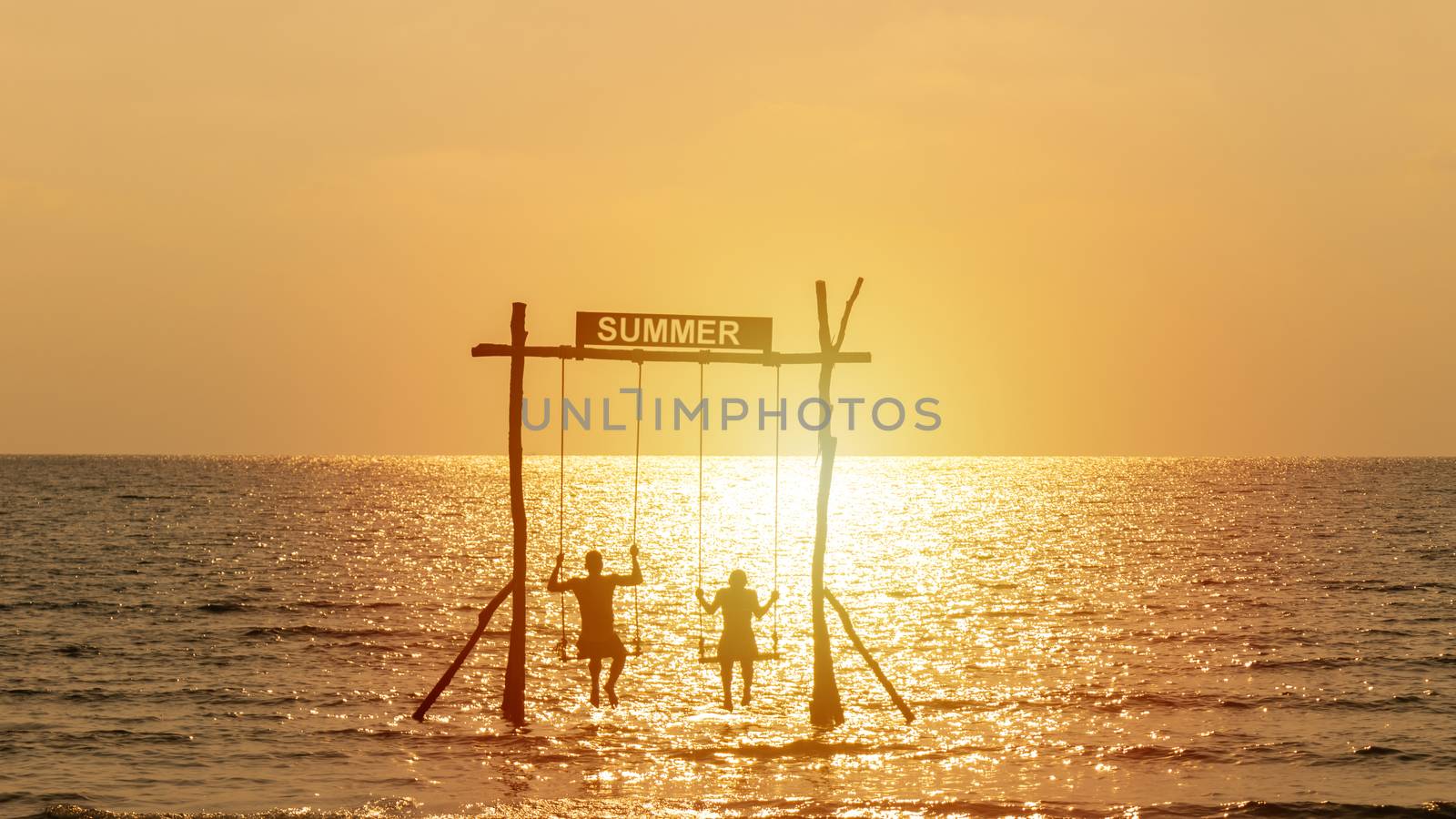 silhouette of happy couple playing swing over the sea with summer sign. happy summer vacation concept