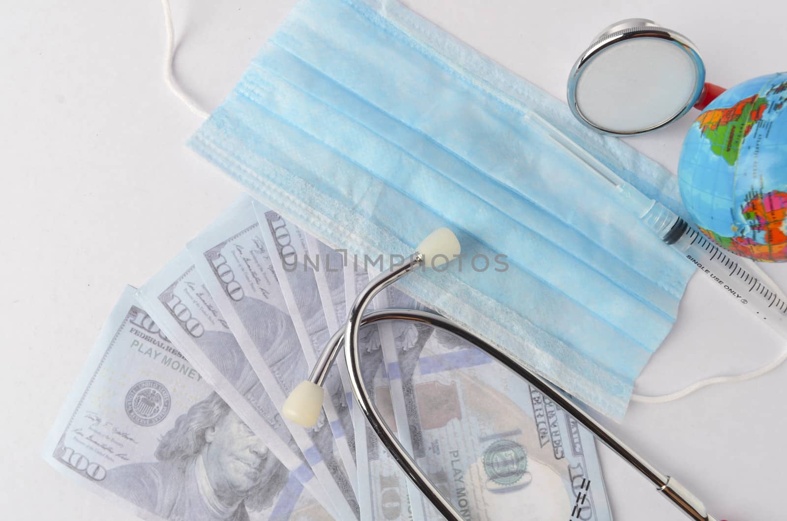 Medical face mask, stethoscope, syringe, world globe and banknotes on white background. Medical concept. Selective focus.