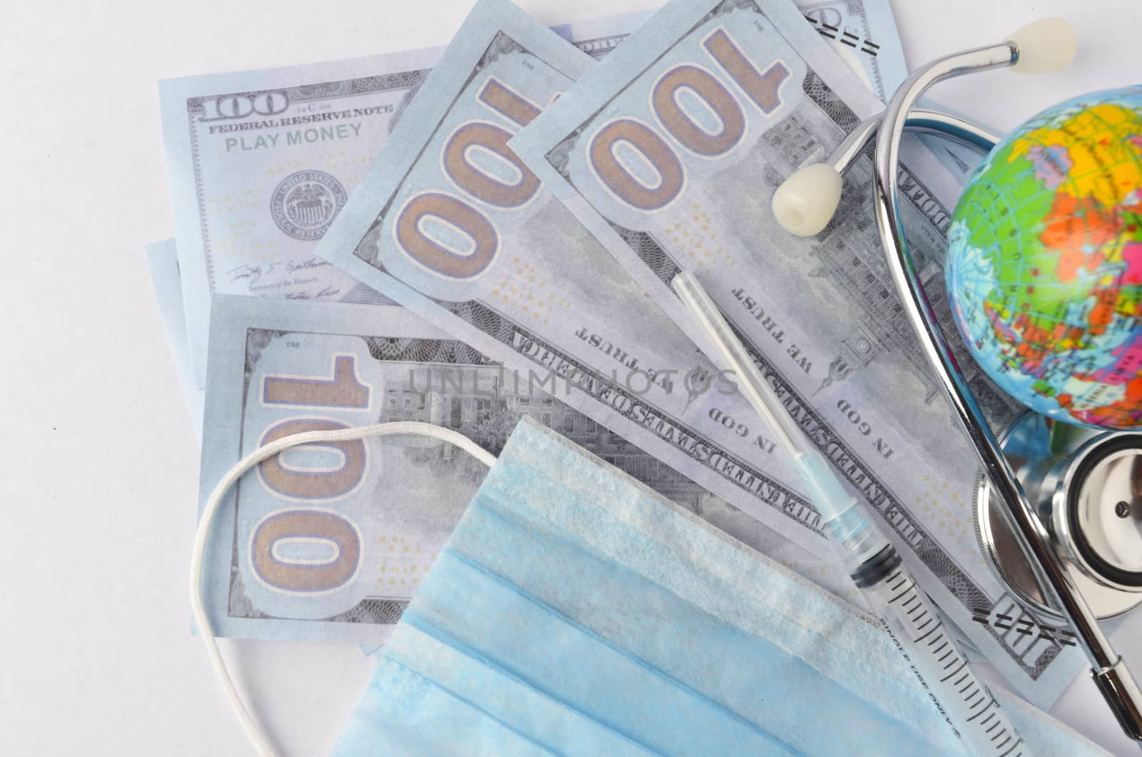 Medical face mask, stethoscope, syringe, world globe and banknotes on white background. Medical concept. Selective focus.