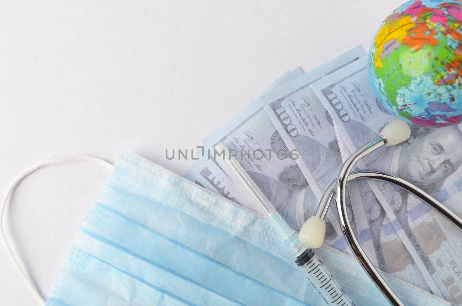 Medical face mask, stethoscope, syringe, world globe and banknotes on white background. Medical concept. Selective focus.