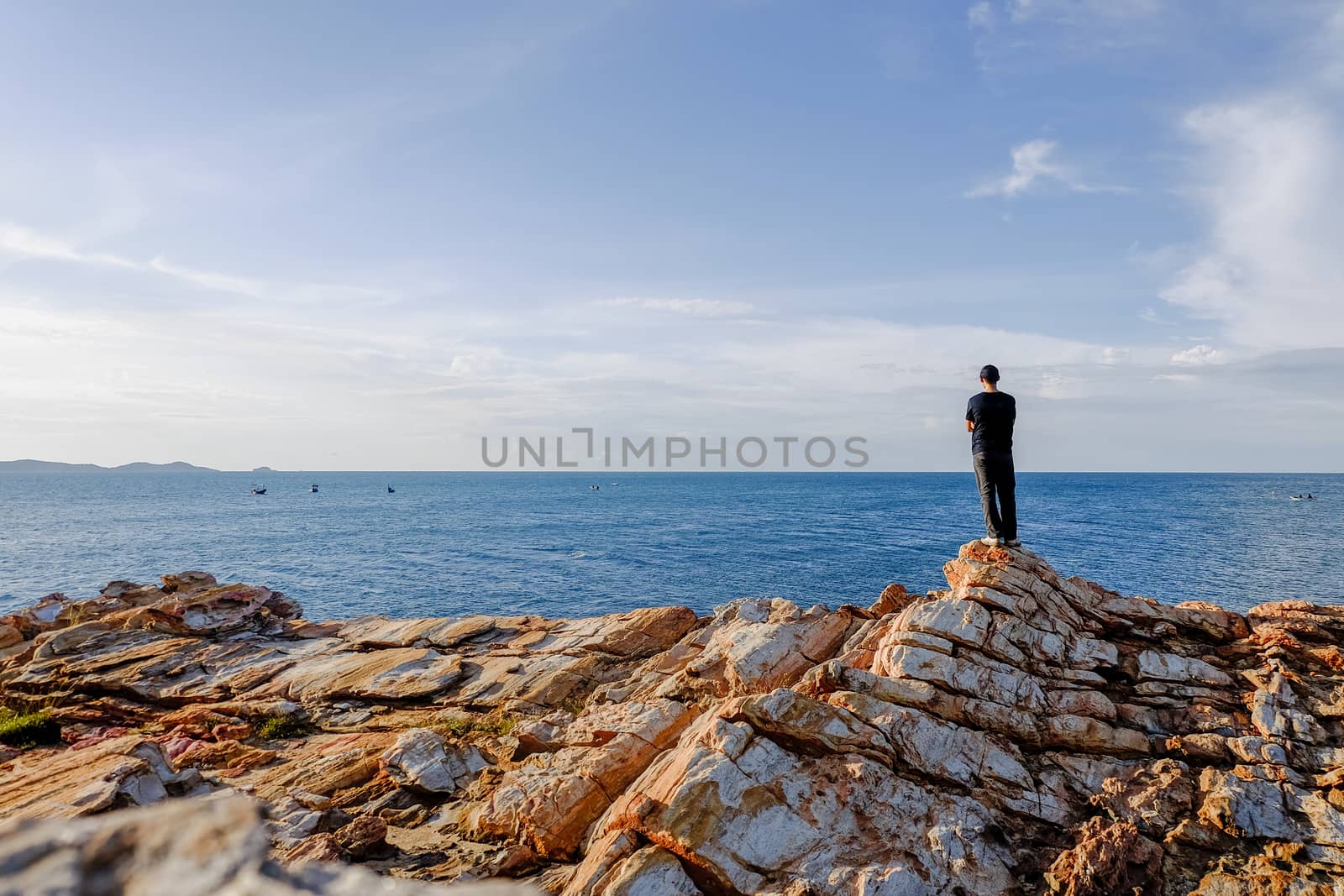 man stood and folded his arms and stood watching the view at Khao Laem Ya, Rayong, Thailand.