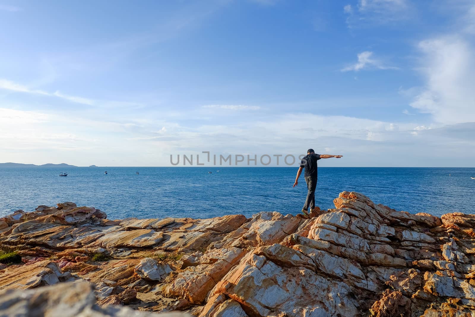 man stands his arms on a rock by suthipong