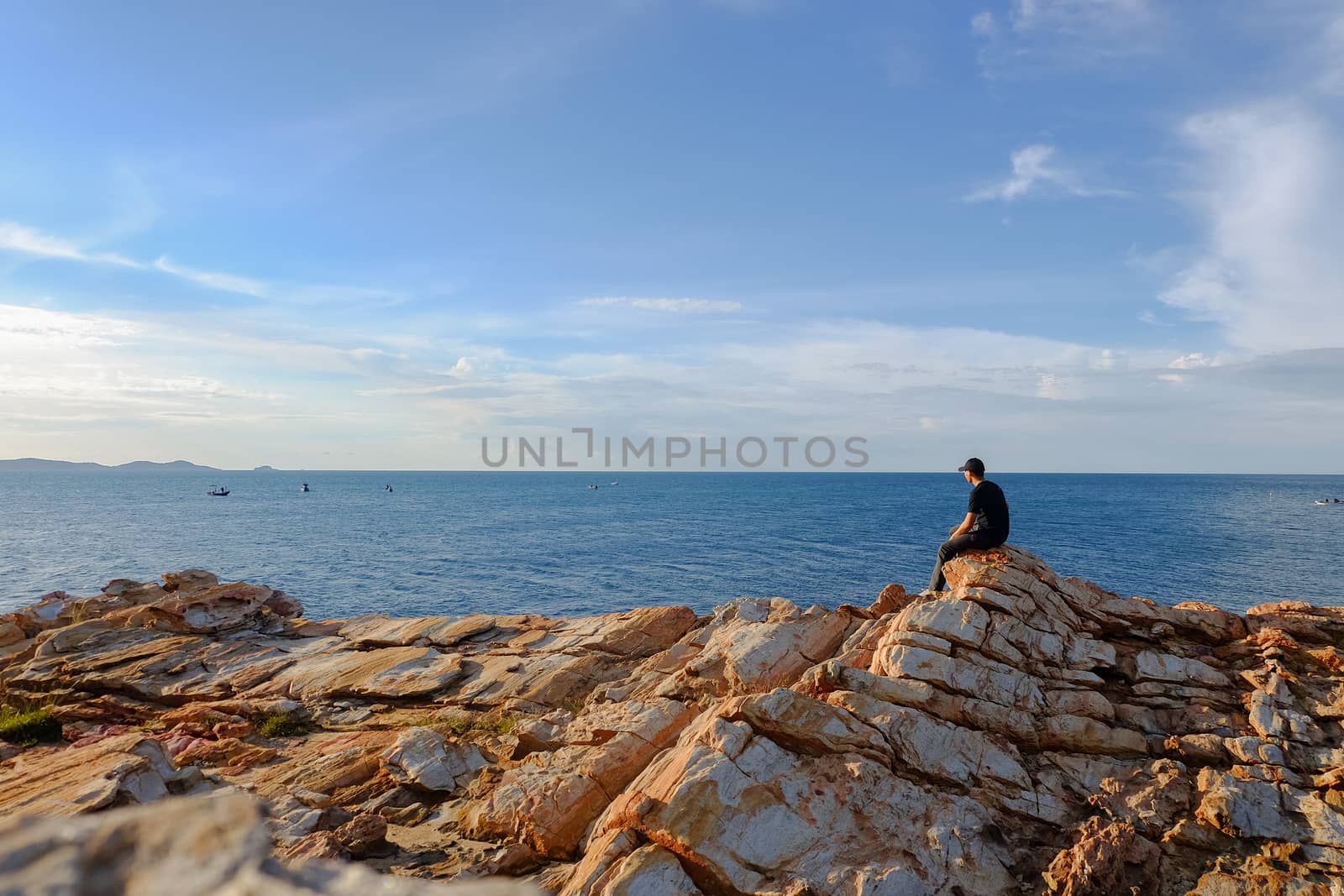 man sitting on a rock by the sea at Khao Laem Ya, Rayong, Thailand