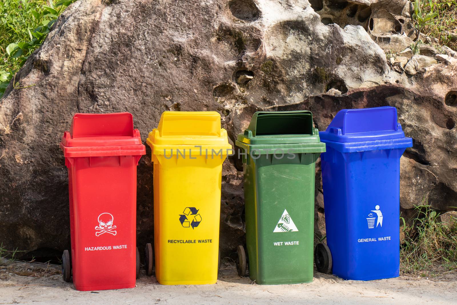 different colored trash containers for garbage separation with sign and icon near the beach for tourist