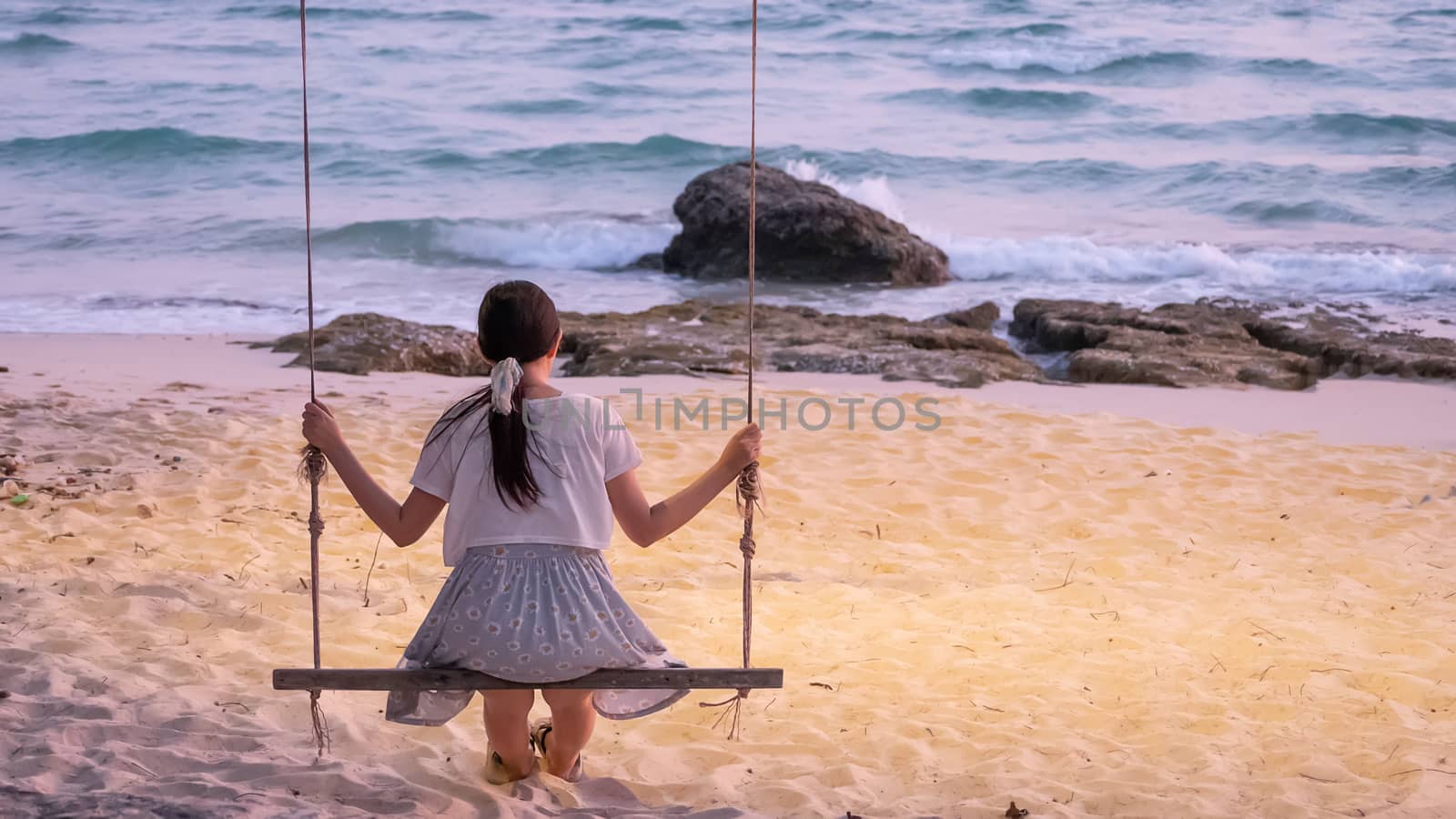 lonely Asian woman sitting on swing at the beach 