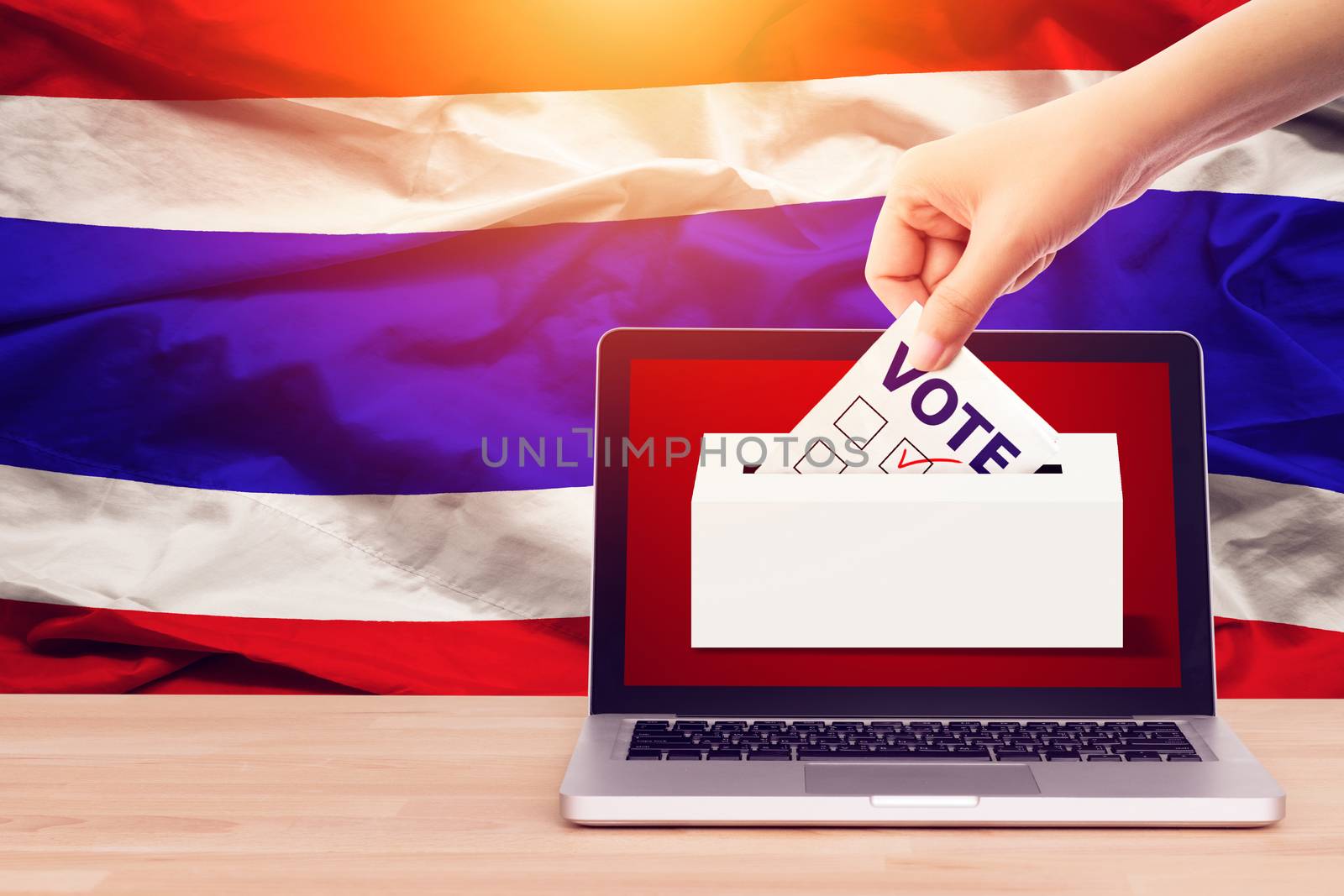 online vote , poll, exit poll for Thailand general election concept. close up hand of a person casting a ballot at elections during voting on canvas Thailand flag background.