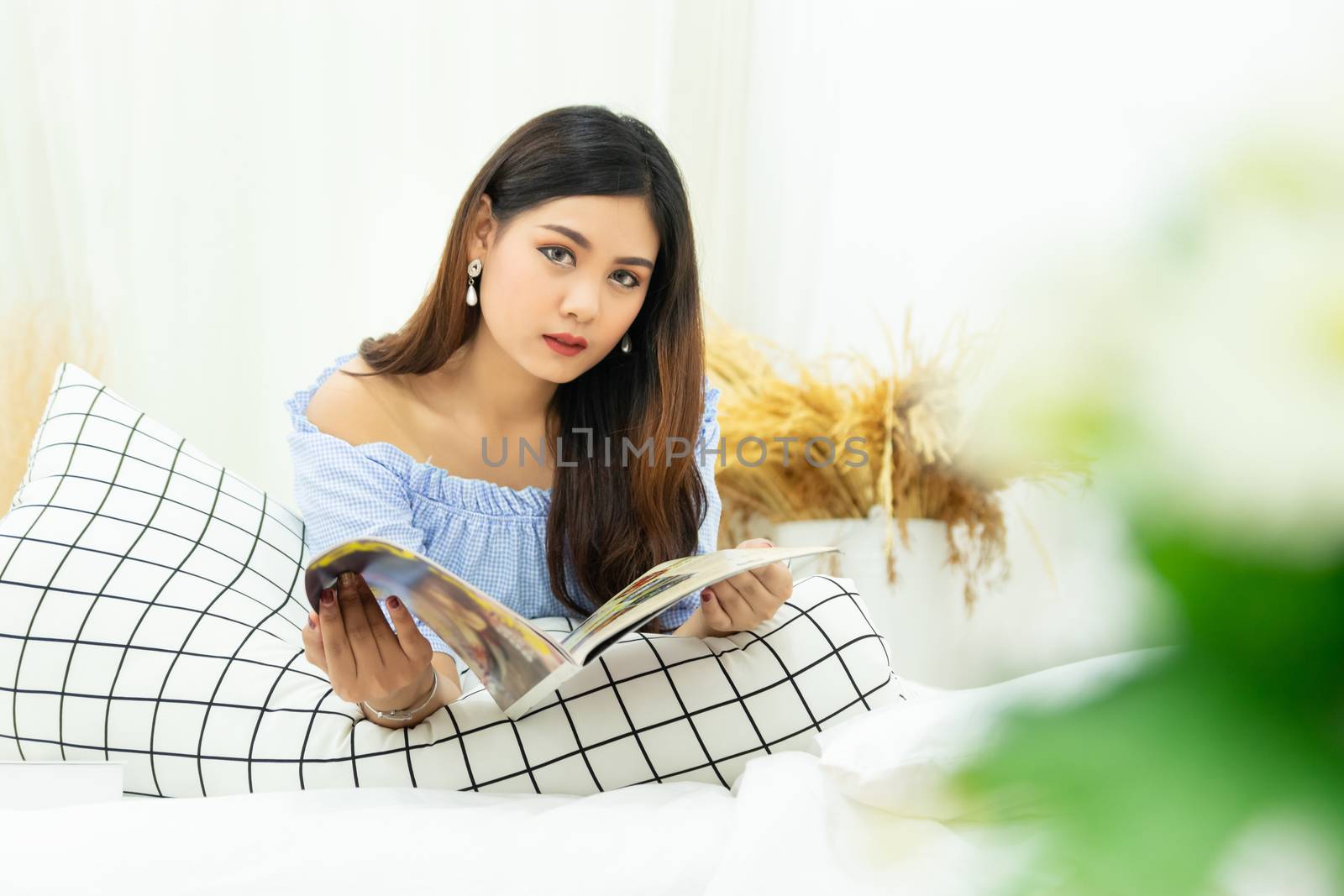 beautiful Asian woman lying on white cozy bed reading a book enjoys of rest at comfort home by asiandelight