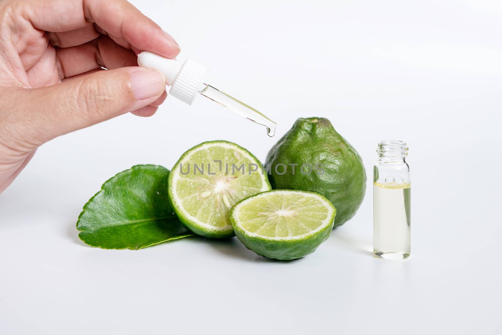 bergamot serum, organic products made from natural concept. woman hand holding glass dropper for dermatologist testing decorate with slide kaffir limes ,kaffir leaf on white background.