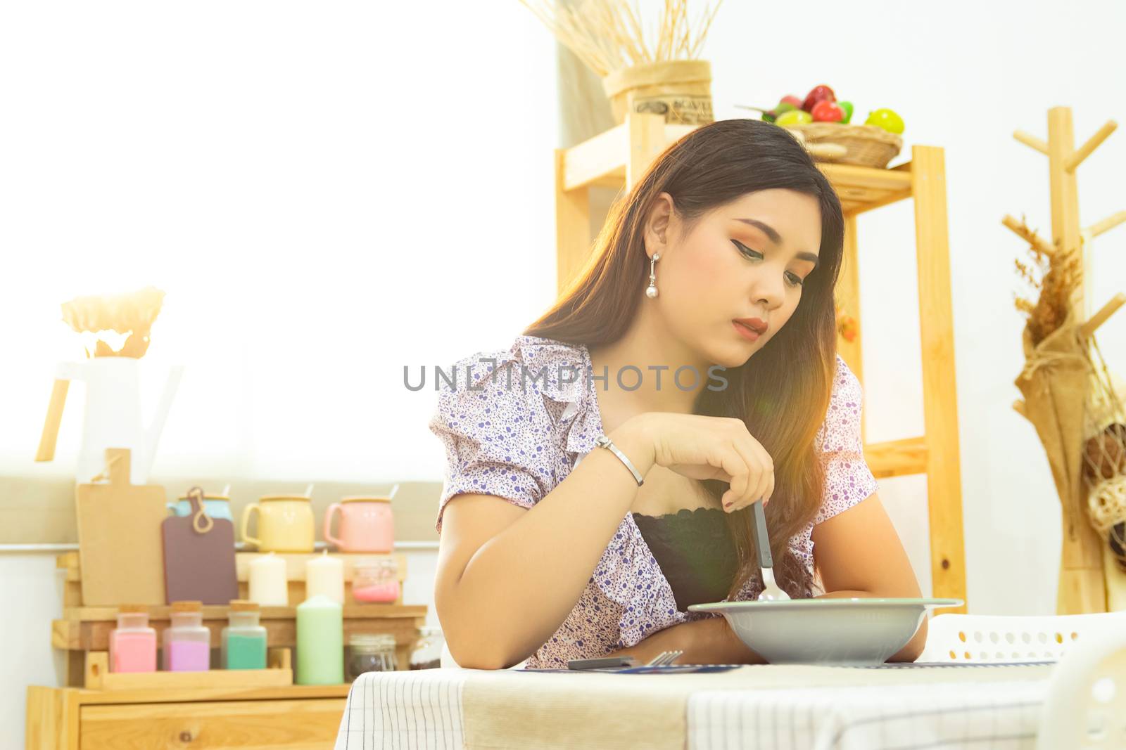 lonely Asian woman sit at the table eating meal in the kitchen alone in the morning with beautiful sunshine light with copy space