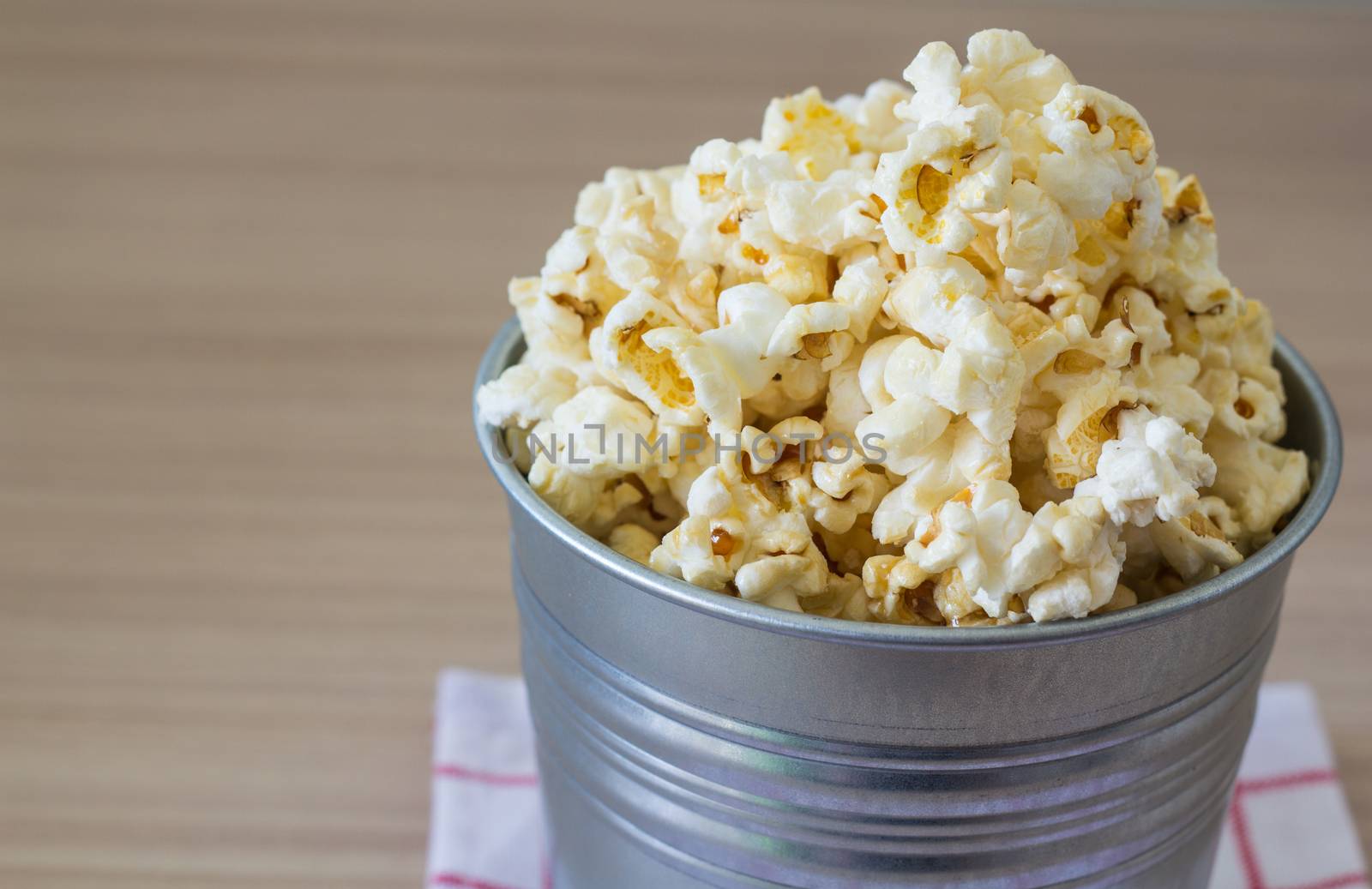 Picture of popcorn in steel bucket on wooden background
