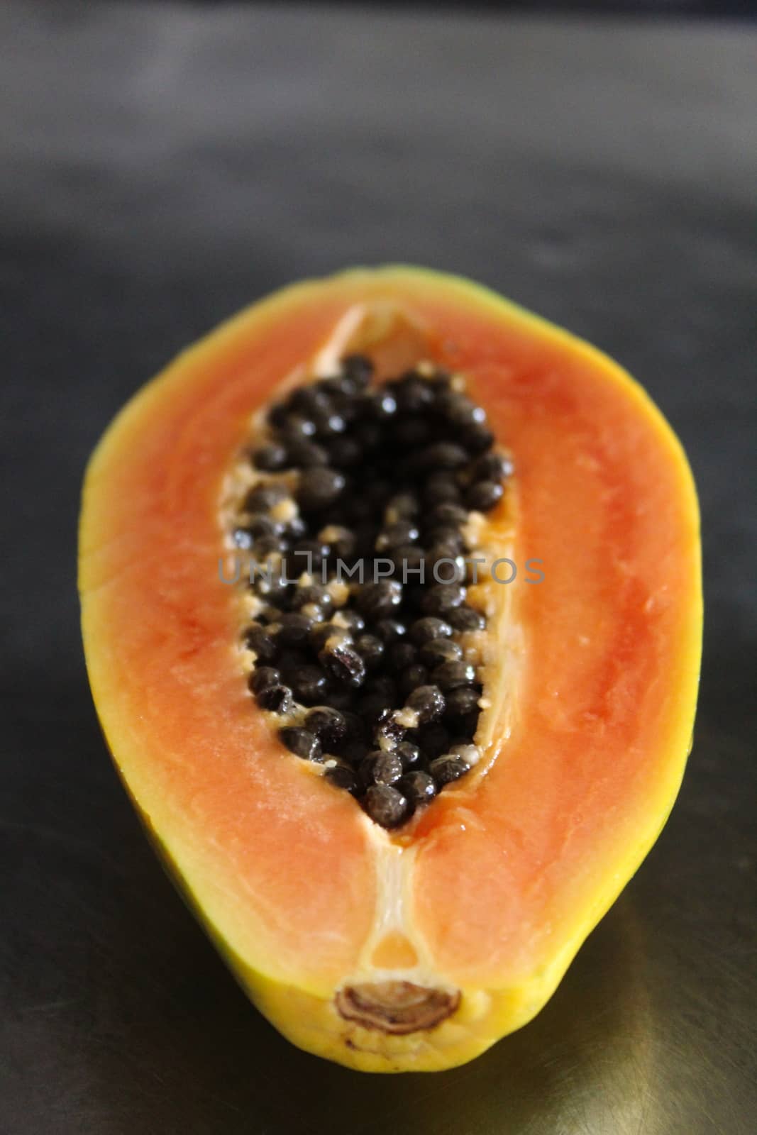 Vertical image of a cut half of a papaya fruit.