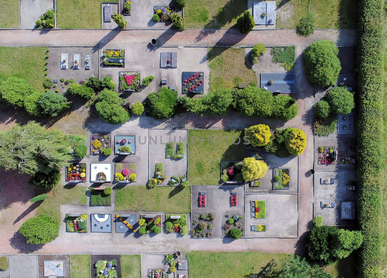 Aerial photo of a cemetery near a village, graves with flowers, colorfully, with the drone from above