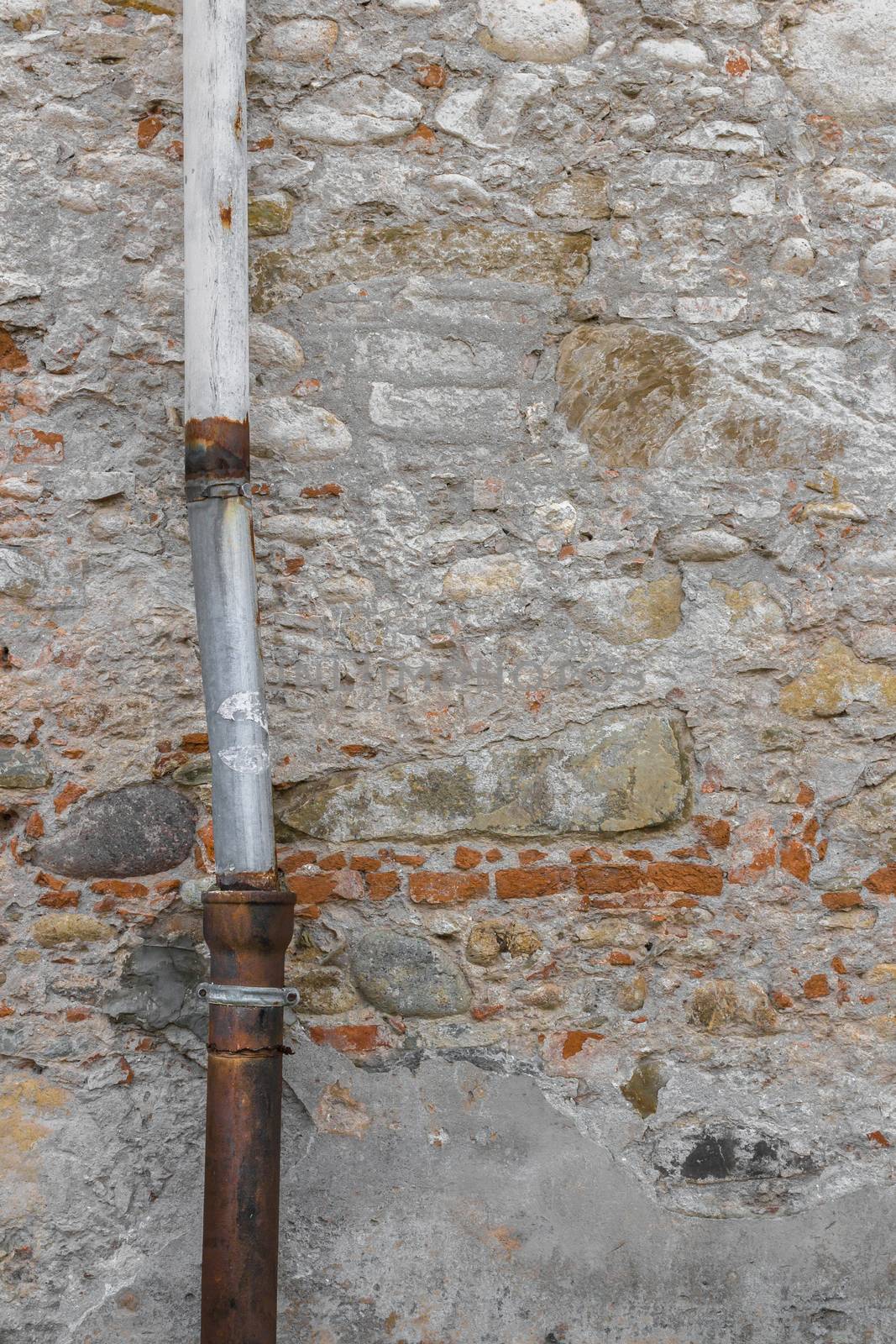 Detail of a downpipe against a brick wall.