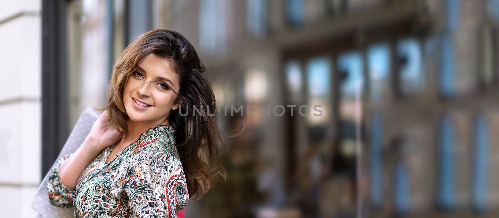 Advertisement banner - happy young woman with shopping bags is looking at camera and smiling while doing shopping in the city ( copy space)