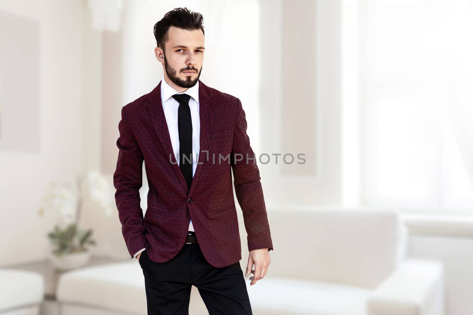 Handsome and elegant fashionable man or businessman posing in luxury interior of a bright room ( mixed).