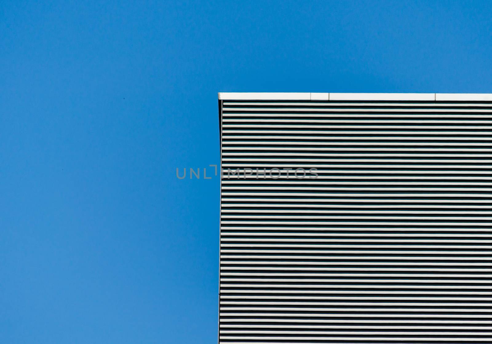 striped wall of a gray tall building against a blue sky