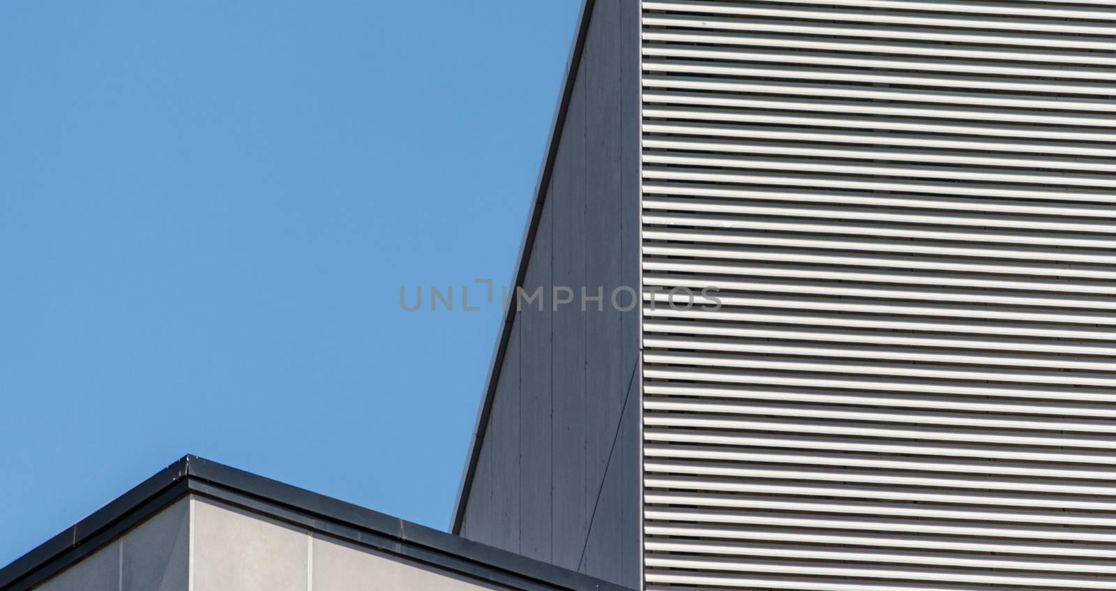 striped wall of a gray tall building against a blue sky