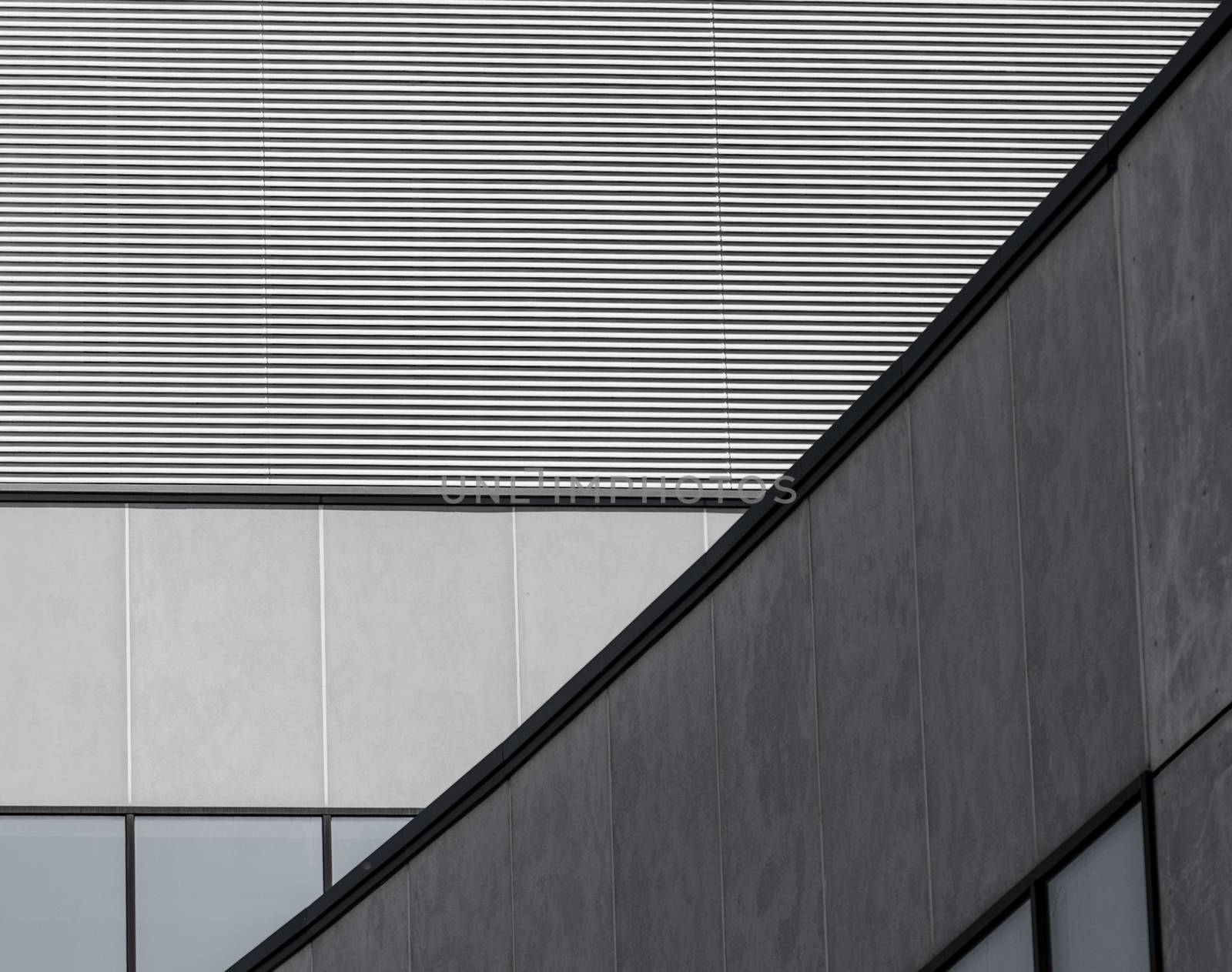 fragment of gray concrete building with a striped wall and empty windows closeup