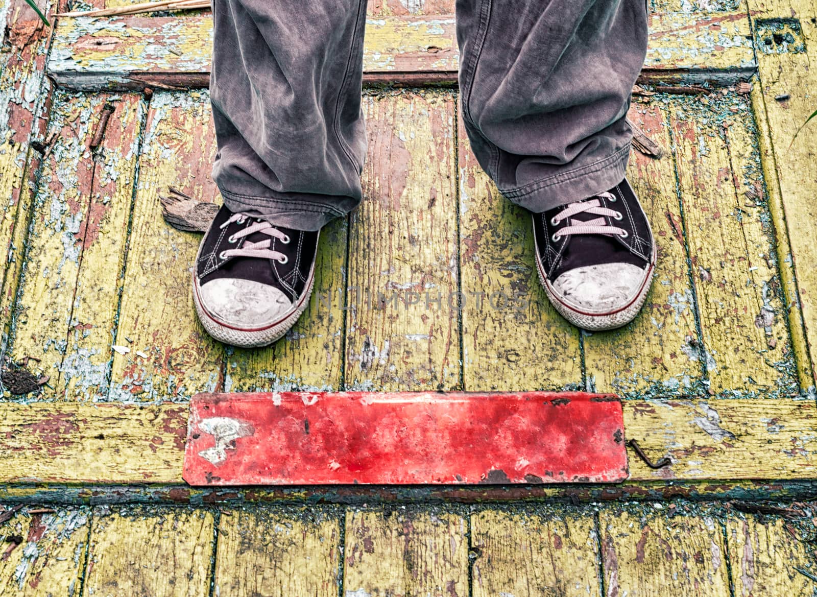 legs of a man in old dirty shoes on a yellow wooden floor close up