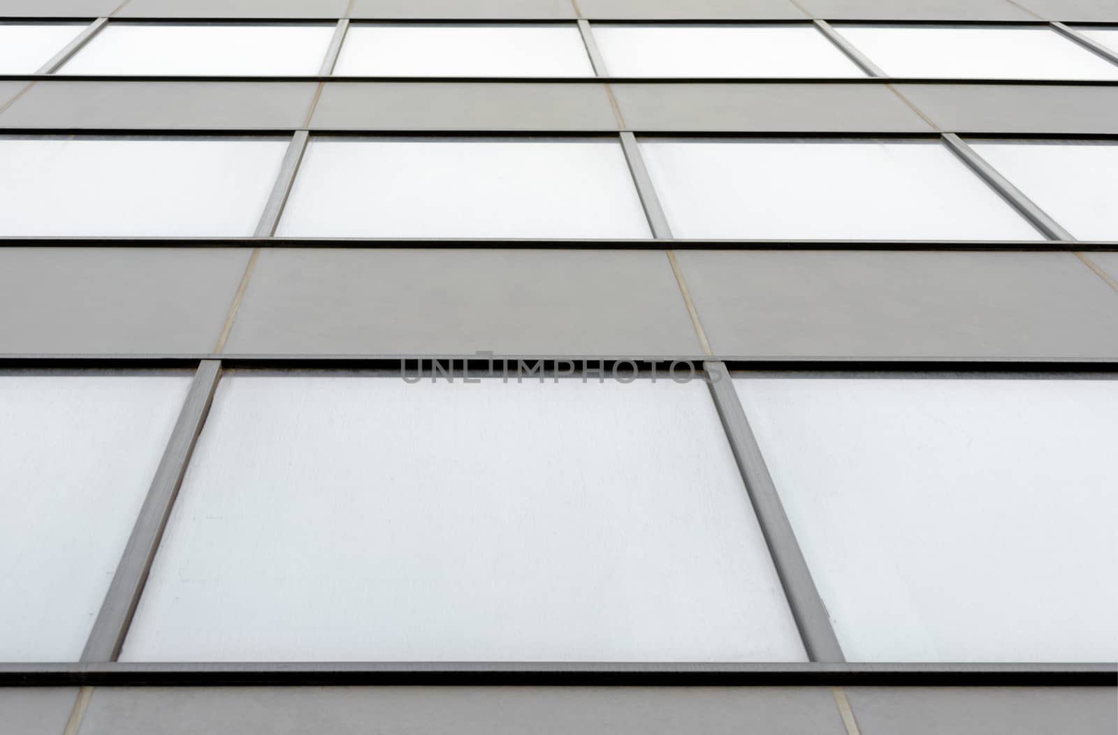 fragment of the wall and windows of a modern tall office building without people  abstract architectural monochromatic background