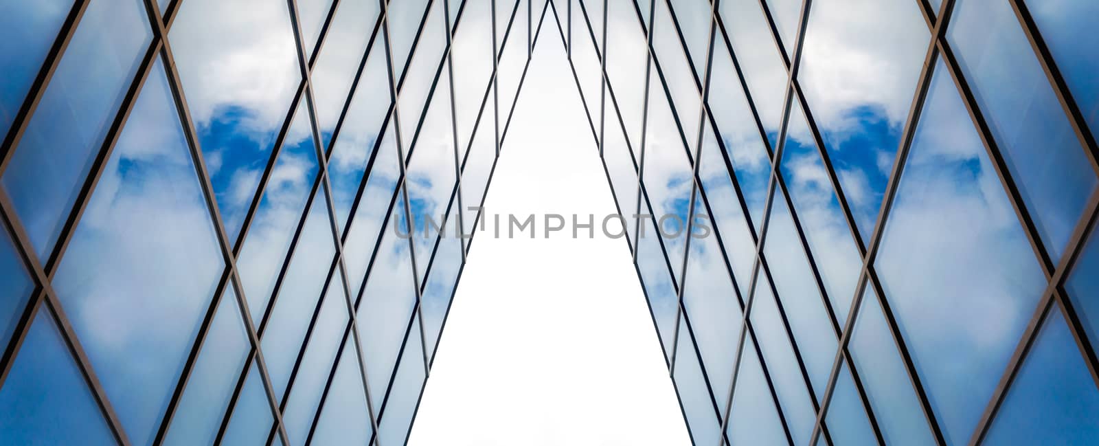 reflection of blue sky with white clouds in a window of a tall office building abstract architectural background