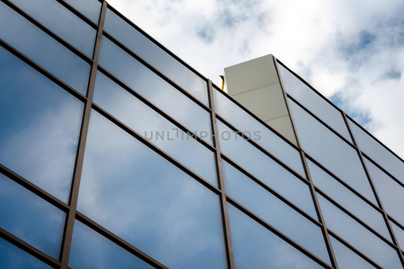 reflection of blue sky with white clouds in a window of a tall office building abstract architectural background