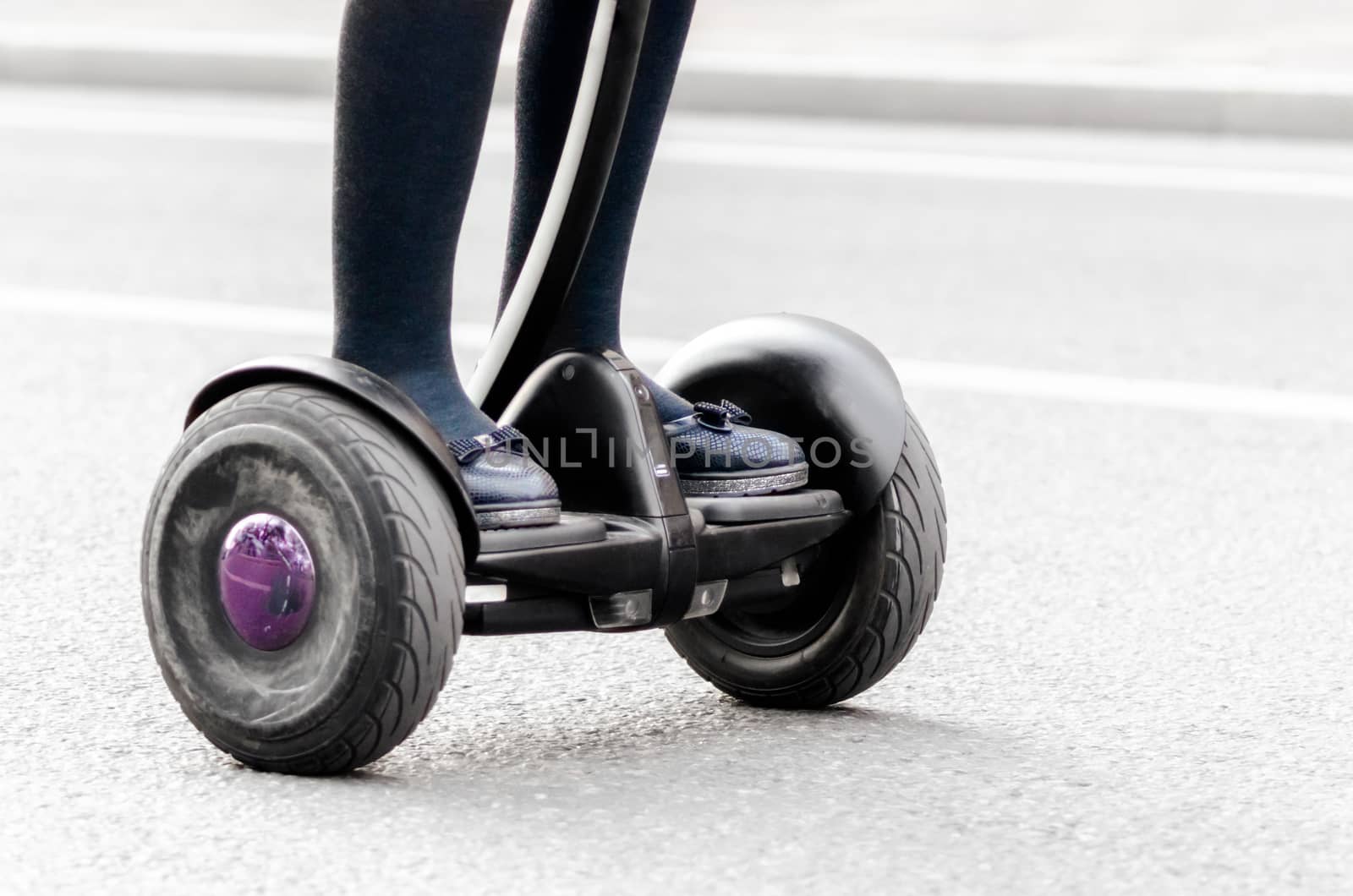 female legs on electric scooter on a city street closeup