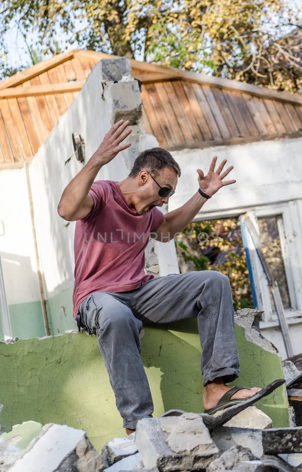 young athletic man in jeans and t-shirt plays out a disaster in a ruined house