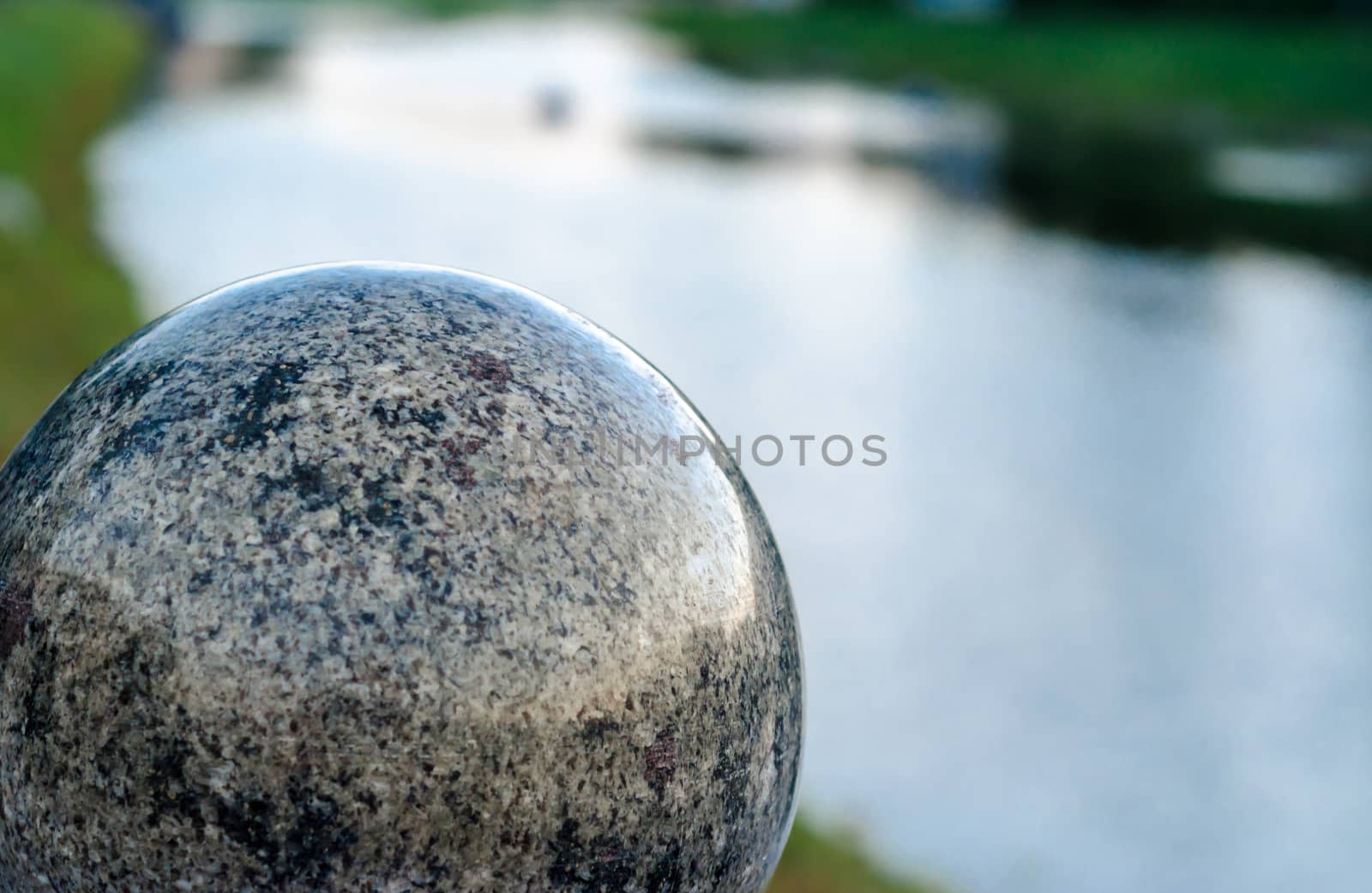 decorative marble ball against the background of the river in the evening