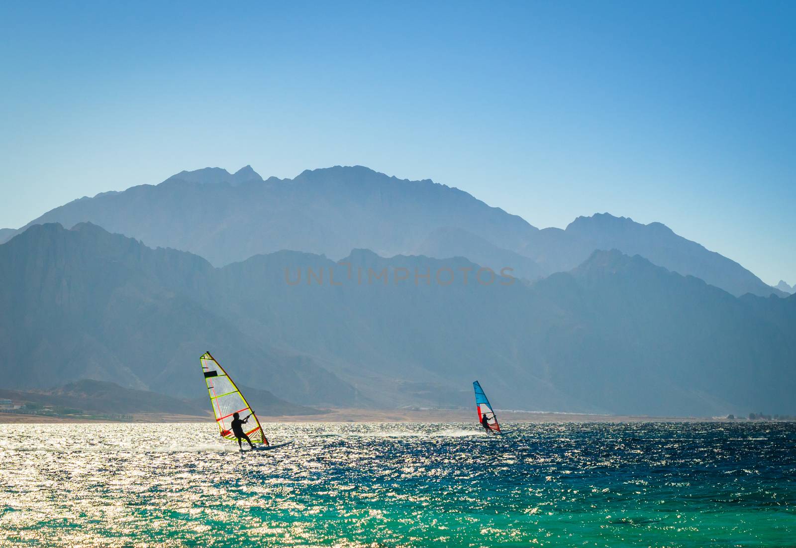 surfers ride in the sea on the background of the rocky coast in Egypt Dahab