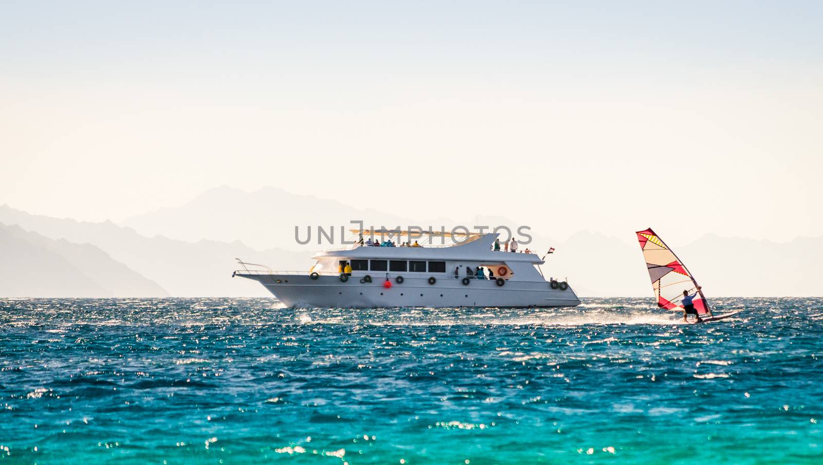 big boat and a surfer in the sea on the background of a rocky coast in Egypt Dahab