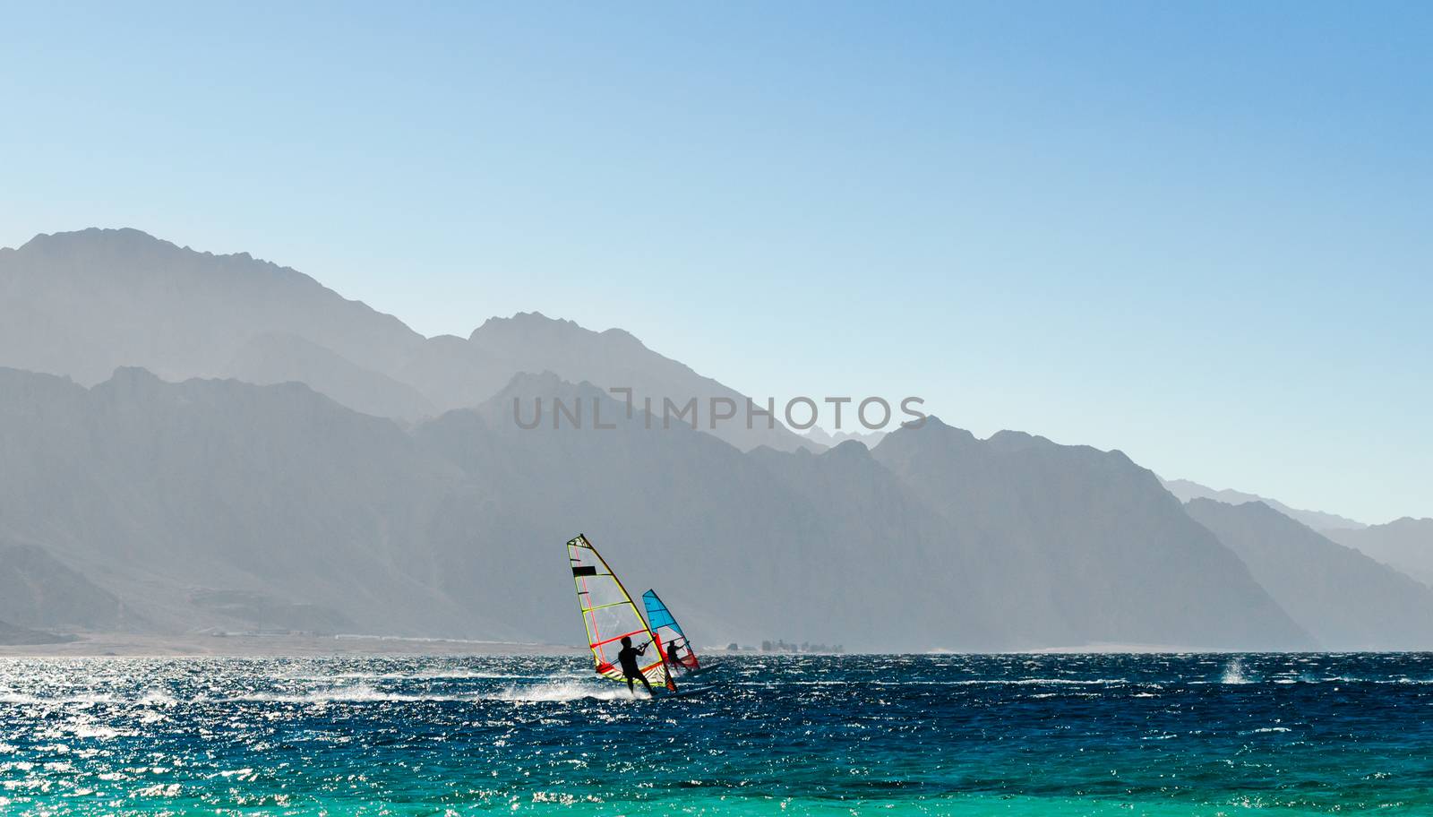 two windsurfers ride on the background of high rocky mountains in Egypt Dahab
