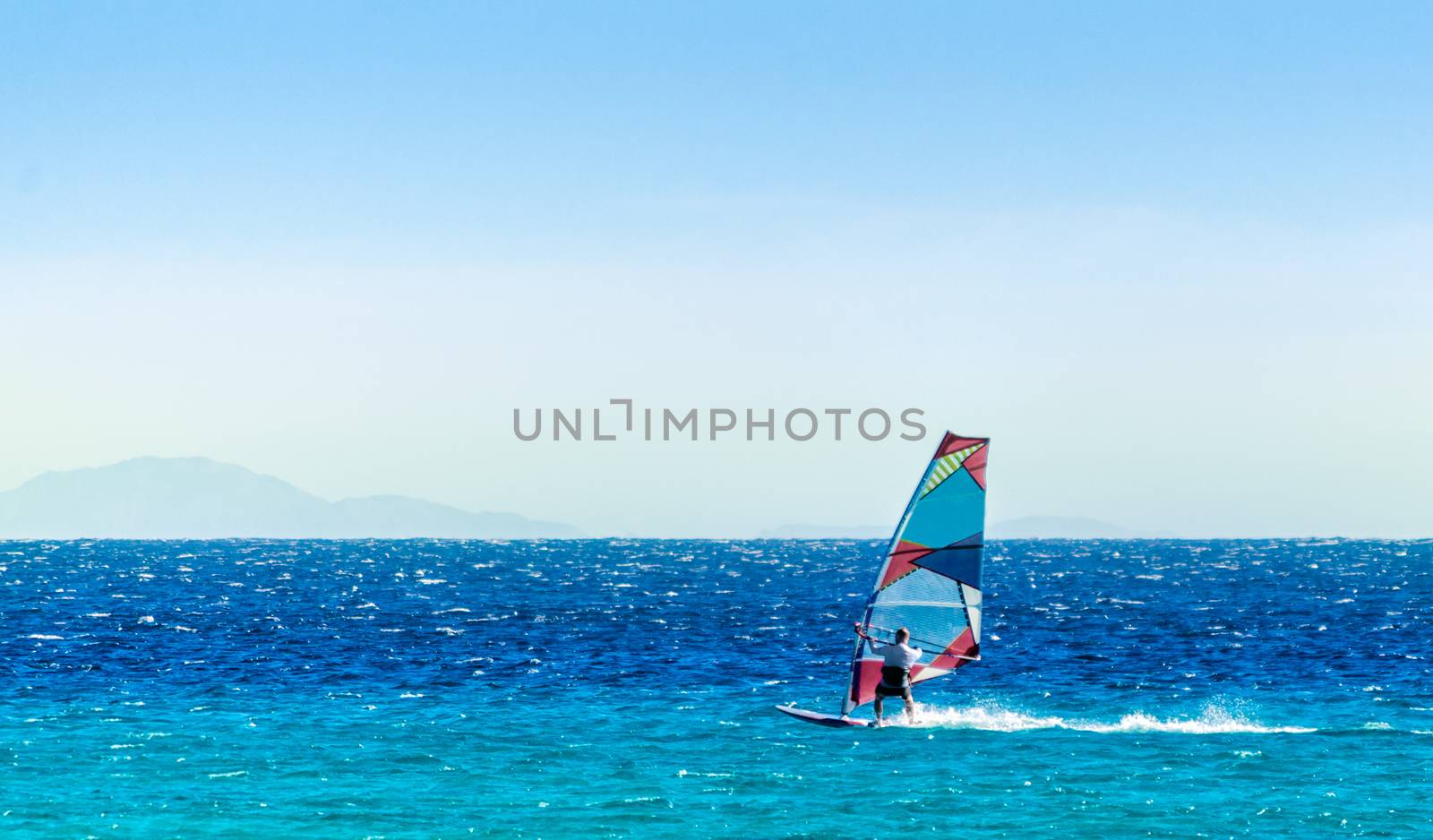 windsurfer on the background of high mountains rides on the waves of the Red Sea in Egypt Dahab South Sinai